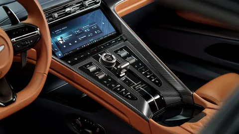 Aston Martin centre console with rows of physical switches, the rotary controller and the infotainment touchscreen above.