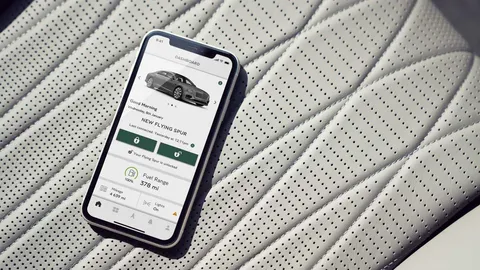 The My Bentley app on a phone lying on quilted, perforated white leather, its home screen showing a New Flying Spur with a greeting and fuel range.